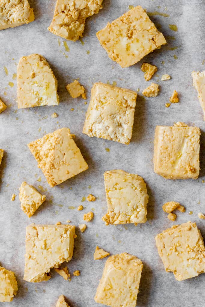 Chunks of uncooked tofu on baking tray.