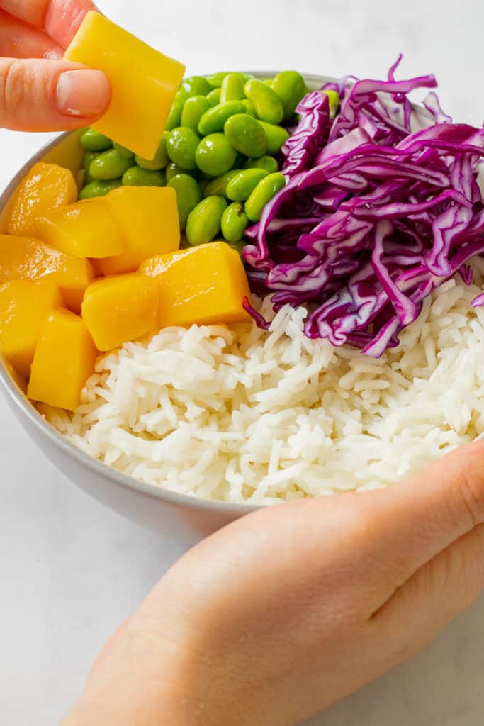 Rice, red cabbage, edamame beans and mango in a bowl.