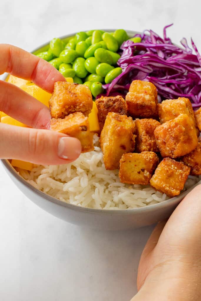 Adding the tofu to the chilli tofu poke bowls.