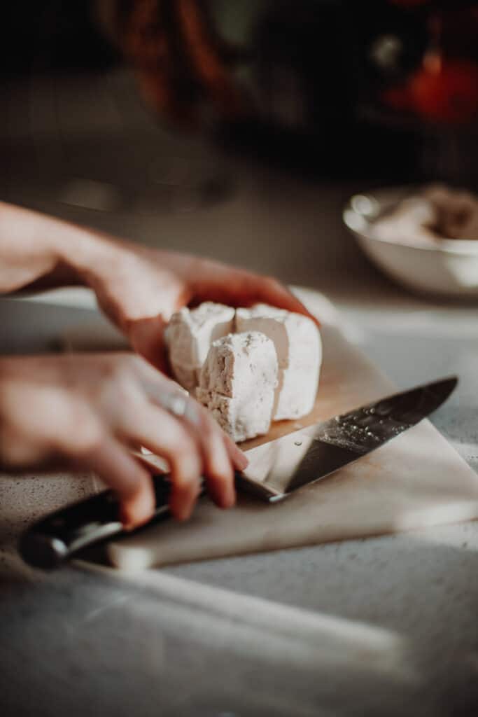Chopping tofu into chunks.