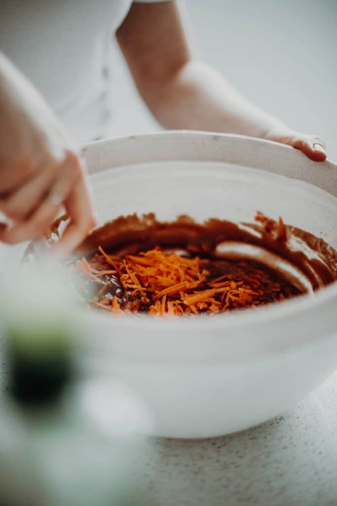 Mixing grated sweet potato into the wet ingredients.
