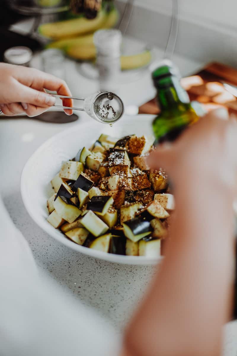 Adding the spices to the chopped aubergine.