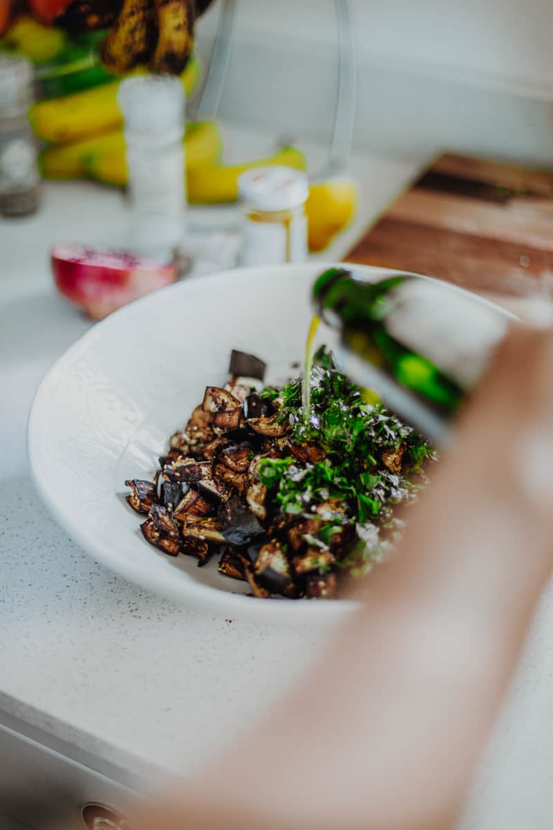 Marinating the cooked aubergine in herbs and olive oil.