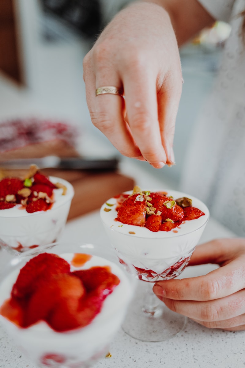 sprinkling pistachios over Strawberry & Elderflower Fools - Vegan, GF & Healthy! Georgie Eats.