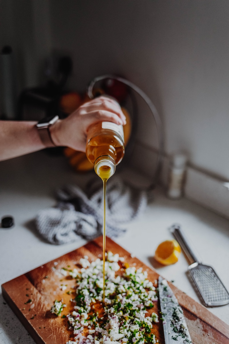 pouring olive oil onto feta salsa