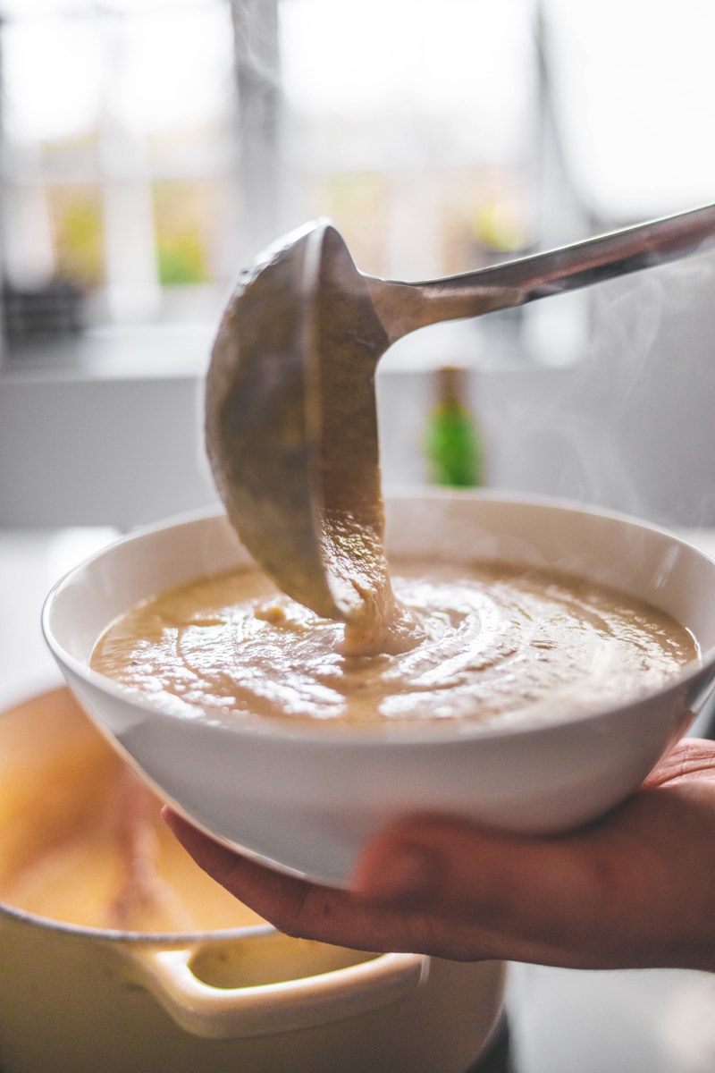 serving the truffled cauliflower soup into a bowl