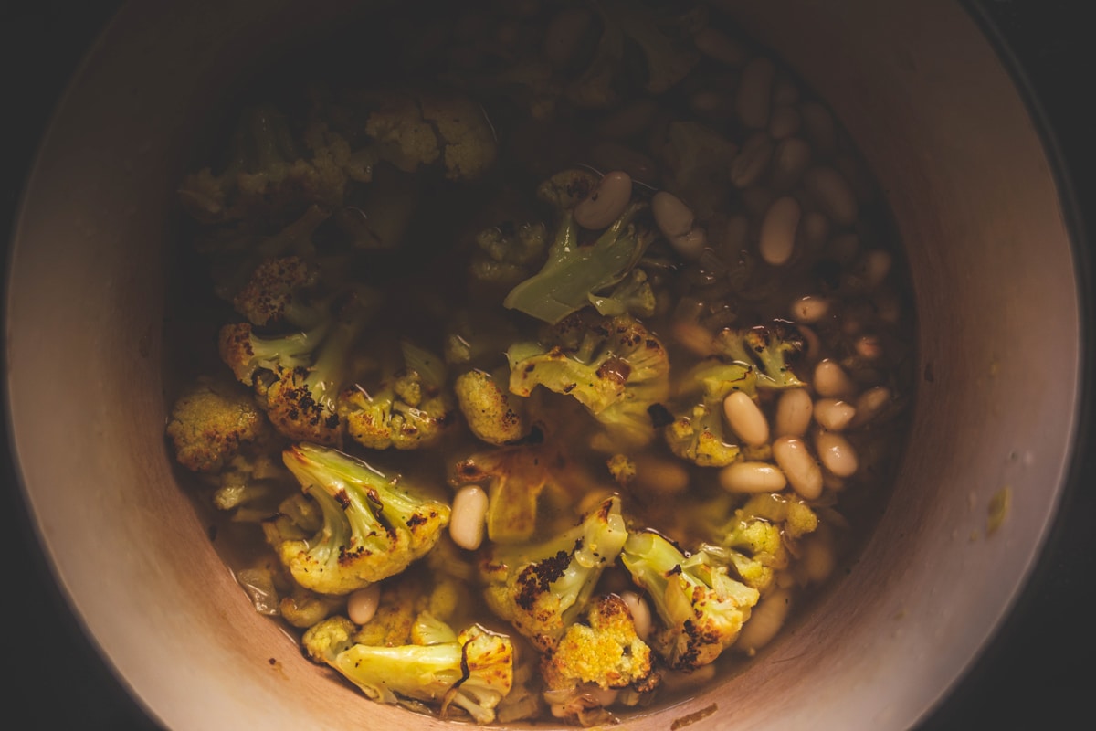 a saucepan with cannellini beans, stock and cauliflower