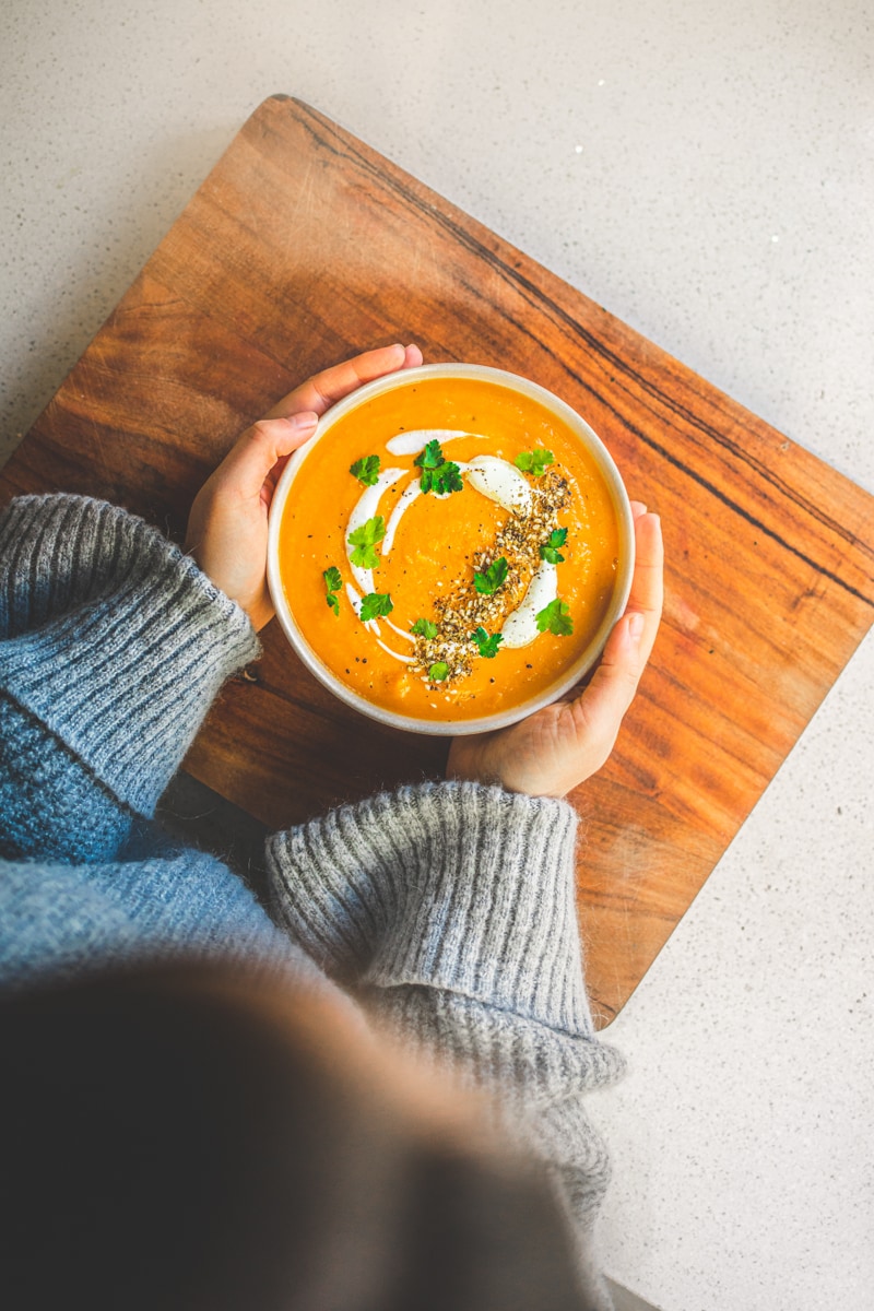 Georgie holding bowl of Carrot & Sweet Potato Soup - Georgie Eats
