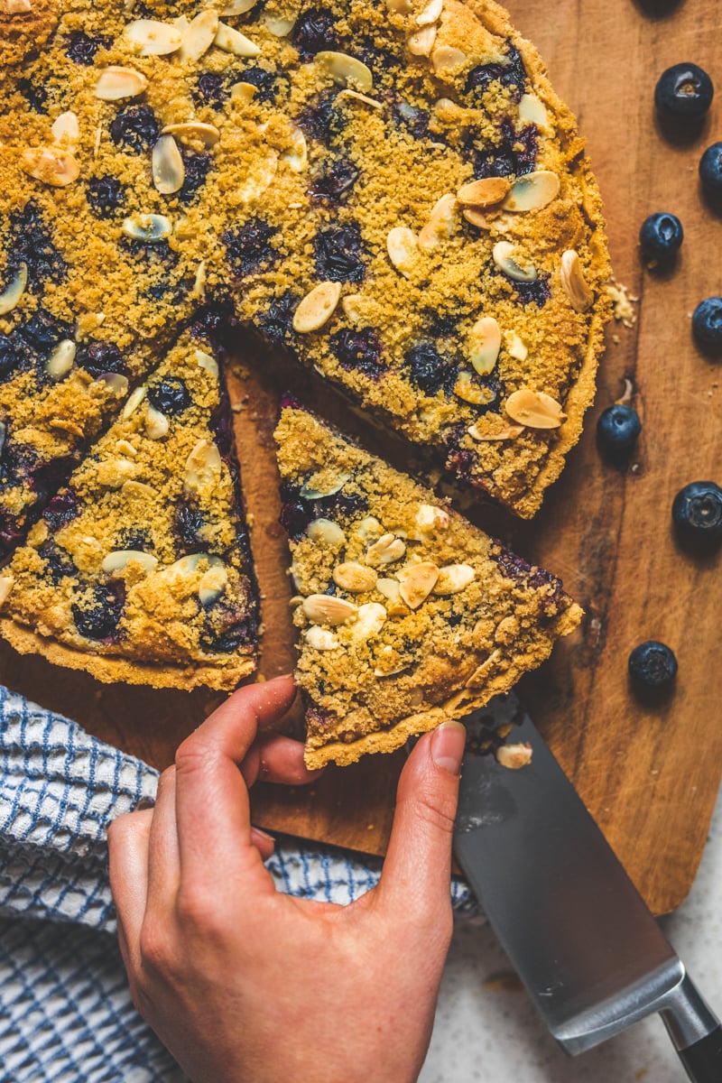 a slice of Blueberry Frangipane Tart - Georgie Eats