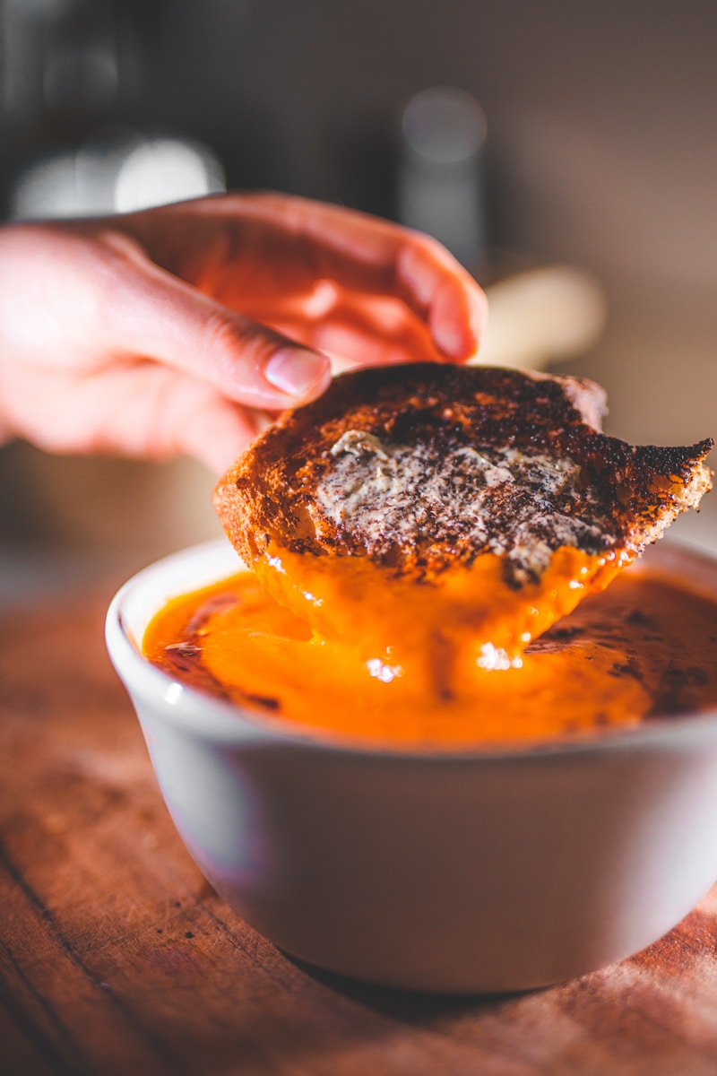 Dipping bread into the Roasted Tomato & Harissa Soup - Georgie Eats