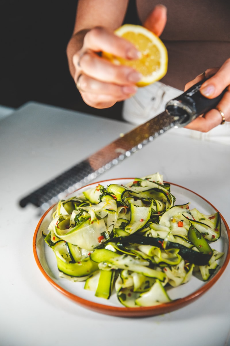 Grating lemon zest over Raw Chilli & Basil Courgette Salad - Georgie Eats