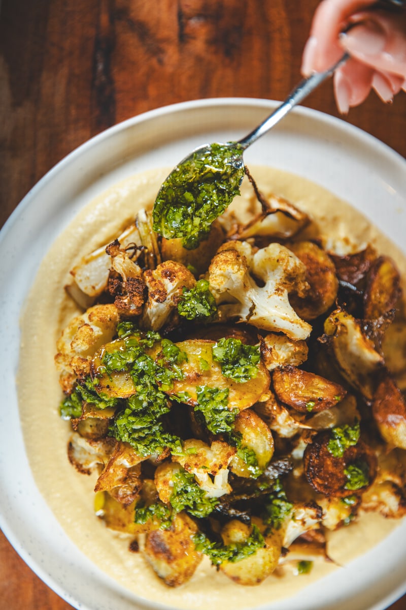 Spooning the Green Harissa on Hummus Plates - Georgie Eats