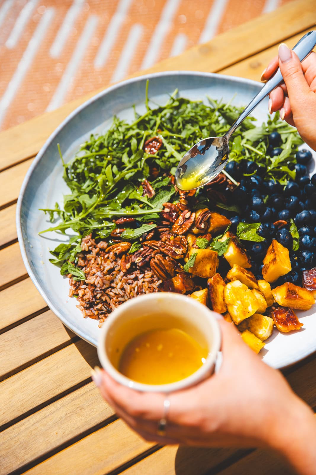 Pouring the dressing over Blueberry, Halloumi & Pecan Salad I Georgie Eats