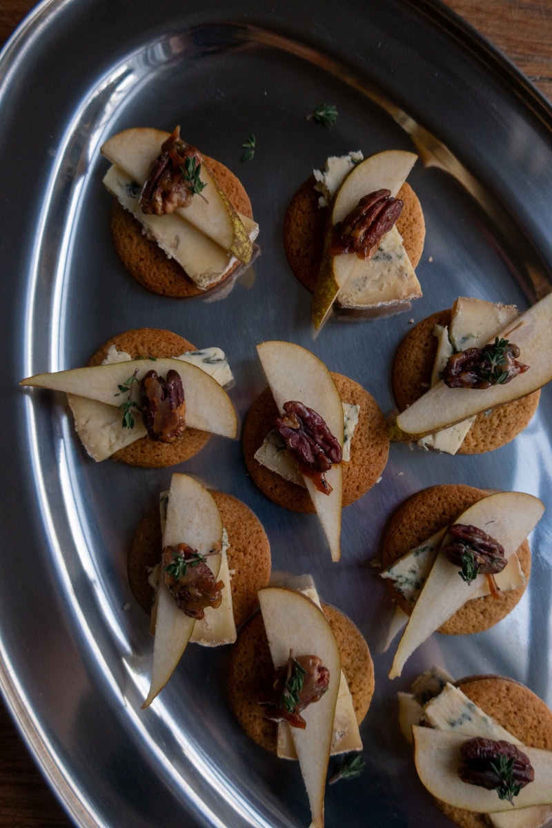 Ginger biscuits topped with slices of stilton and pear, garnished with candied pecans - Georgie Mullen