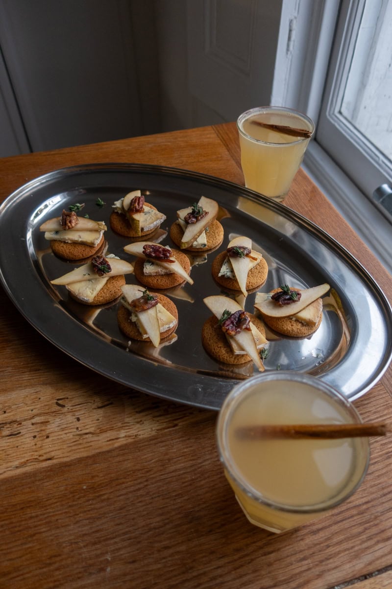 Two glasses of hot apple toddy sat next to a silver tray of biscuit canapes - Georgie Mullen
